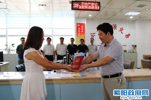 县国土局局长夏德晏郑重的将全县实施不动产权统一登记后的第一份证书交到权利人王连美手中。_副本.jpg