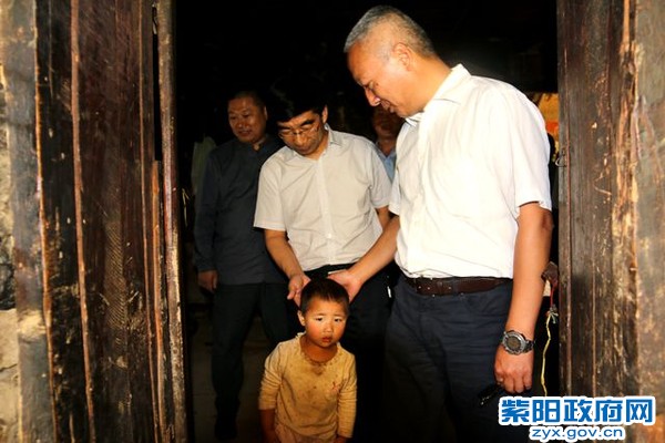 陈勇抚摸着贫困户李兴科的孙子，强调要用好搬迁政策.jpg